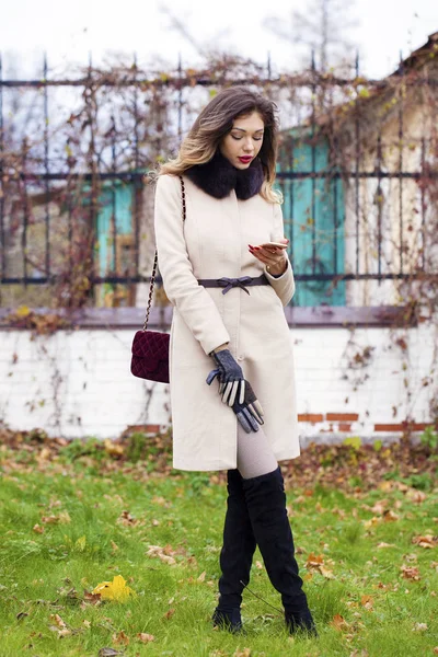 Młoda piękna kobieta w beżowy płaszcz jesień odczytuje wiadomości na — Zdjęcie stockowe