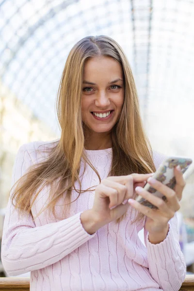 Jeune femme blonde heureuse lisant un message au téléphone — Photo