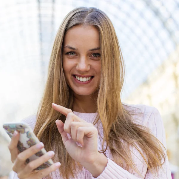 Jovem mulher loira feliz lendo uma mensagem no telefone — Fotografia de Stock