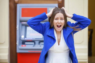 Frustrated young woman stands on against ATM clipart