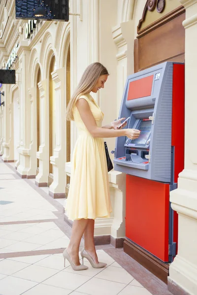 Wanita pirang yang bahagia menarik uang dari kartu kredit di ATM — Stok Foto