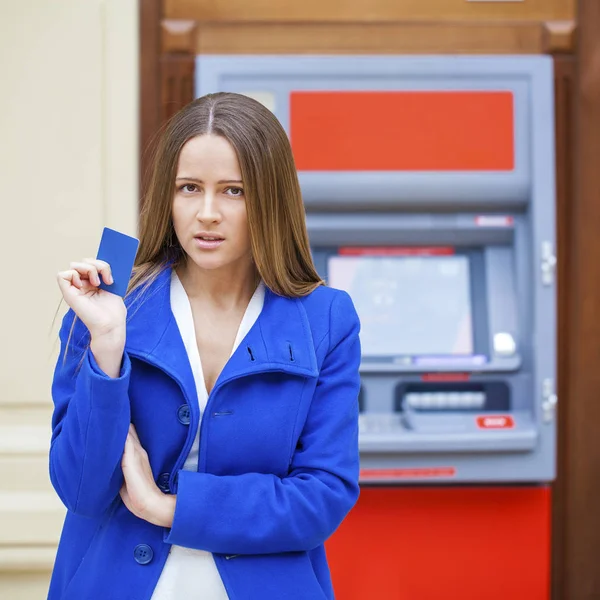 Разочарованная молодая женщина стоит напротив банкомата — стоковое фото