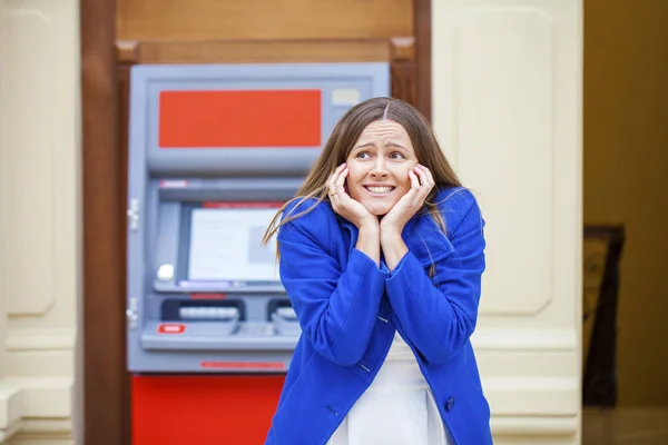 Frustrated young woman stands on against ATM — Stock Photo, Image