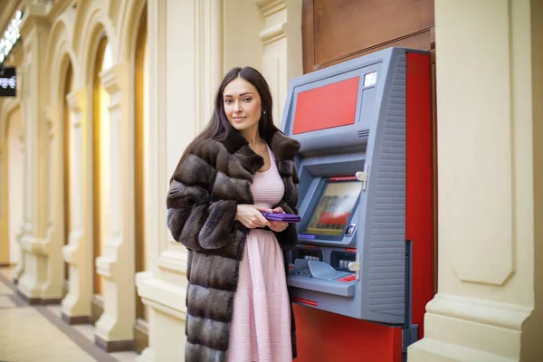 Happy brunette woman withdrawing money from credit card at ATM — Stock Photo, Image