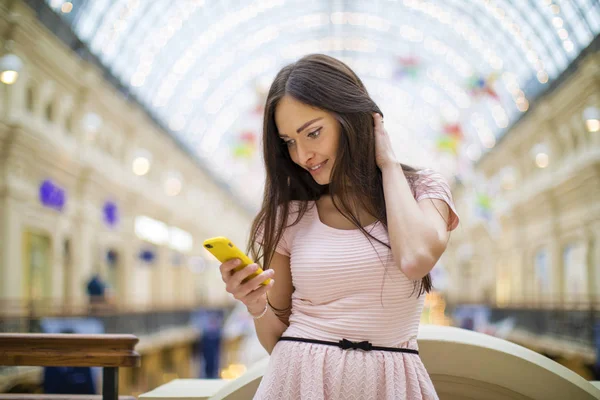 Giovane donna bruna che legge un messaggio al telefono — Foto Stock