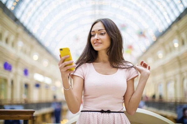 Mladá bruneta žena čtení zpráv na telefonu — Stock fotografie