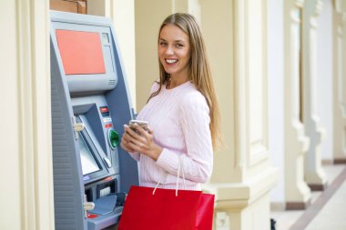 Arka planda alışveriş merkezi Atm üzerinde sarışın kadın