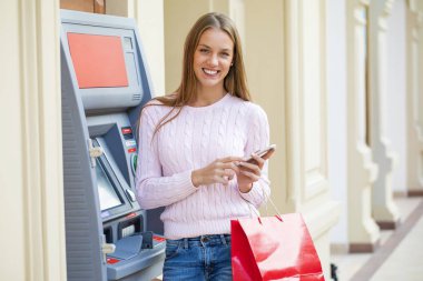 Arka planda alışveriş merkezi Atm üzerinde sarışın kadın