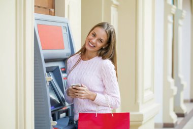 Arka planda alışveriş merkezi Atm üzerinde sarışın kadın