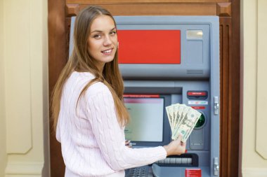 Genç sarışın kadın bir nakit dolar tutuyor