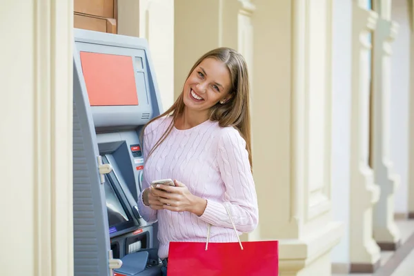 Blondine im Hintergrund in Einkaufszentrum am Geldautomaten — Stockfoto