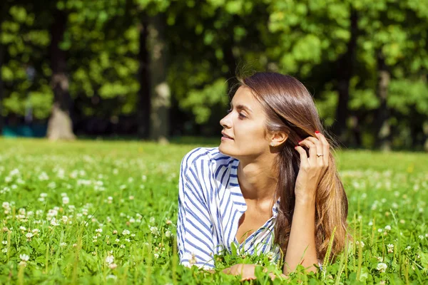 Aantrekkelijke jonge brunette vrouw liggend op groen grasveld op su — Stockfoto