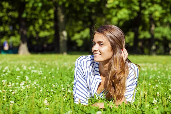 매력적인 젊은 갈색 머리 여자 쓰에 녹색 잔디 필드에 누워 — 스톡 사진