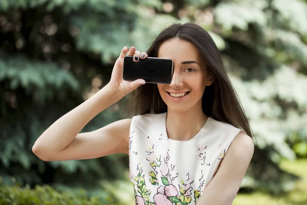 Krásná mladá dívka ukazuje váš smartphone obrazovky — Stock fotografie