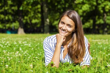 Çekici genç esmer kadın su yeşil çim sahasının yalan