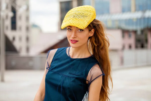 Porträt einer brünetten Frau mit gelbem Hut und blauem Kleid — Stockfoto