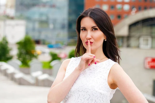 Young beautiful brunette woman has put forefinger to lips as sig — Stock Photo, Image