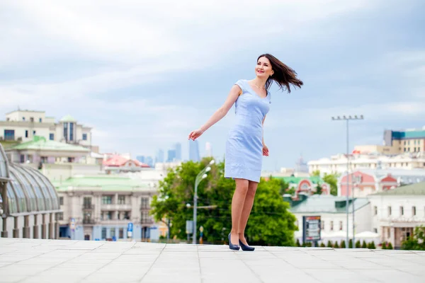 Молода красива жінка в блакитній сукні, що йде на літній вулиці — стокове фото
