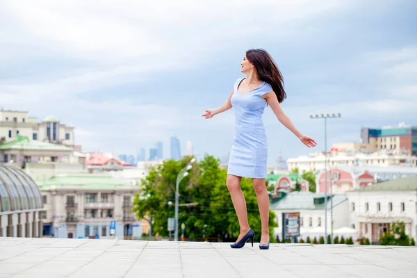 Jovem mulher bonita em um vestido azul andando sobre o stre de verão — Fotografia de Stock