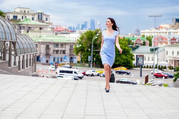 Mladá krásná žena v modrých šatech, chůzi na ulici letní — Stock fotografie