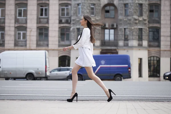 Jovem bela mulher morena em vestido branco andando sobre o str — Fotografia de Stock