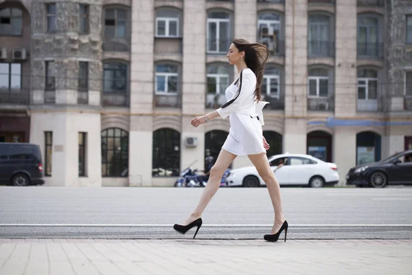 Str の上を歩いて白いドレスの若い美しいブルネットの女性 — ストック写真