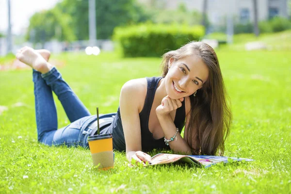 Junge schöne Frau sitzt im Sommerpark — Stockfoto