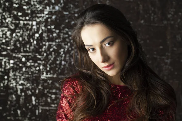 Young brunette woman on dark studio wall background — Stock Photo, Image