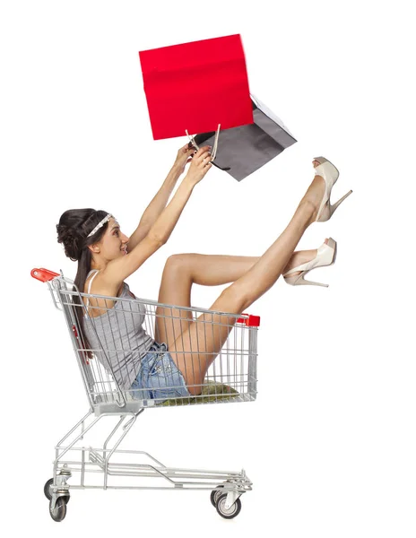 Ung vacker brunett flicka sitter i en tom shopping cart wit — Stockfoto