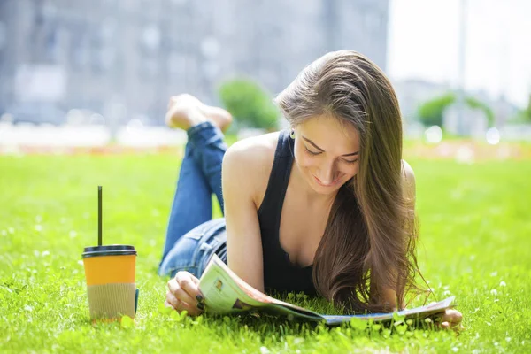 Junge schöne Frau sitzt im Sommerpark — Stockfoto