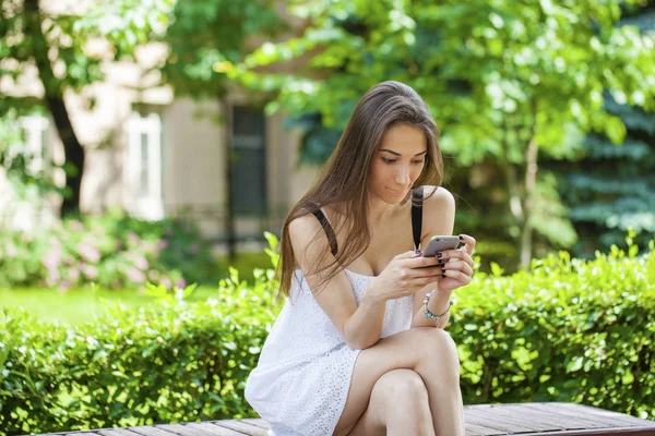 Mladá bruneta žena čtení zpráv na telefonu — Stock fotografie