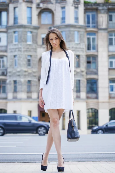 Jeune belle femme brune en robe blanche marchant sur la rue — Photo