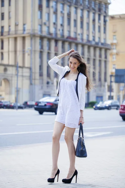 Jovem bela mulher morena em vestido branco andando sobre o str — Fotografia de Stock