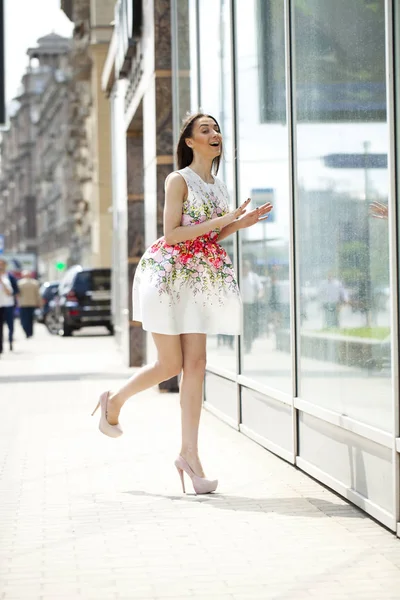 Jonge mooie brunette vrouw in witte bloemen jurk lopen op — Stockfoto