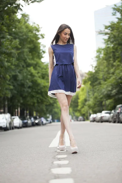 Ung vacker kvinna i en blå kort klänning går på vägen — Stockfoto