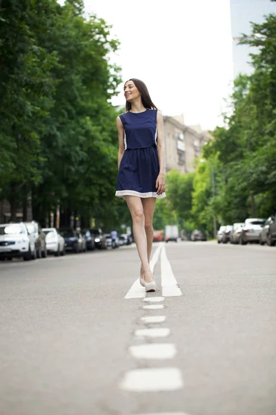 Young beautiful woman in a blue short dress walking on the road — Stock Photo, Image
