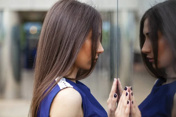 Senhora elegante em vestido azul posando perto de parede espelhada — Fotografia de Stock