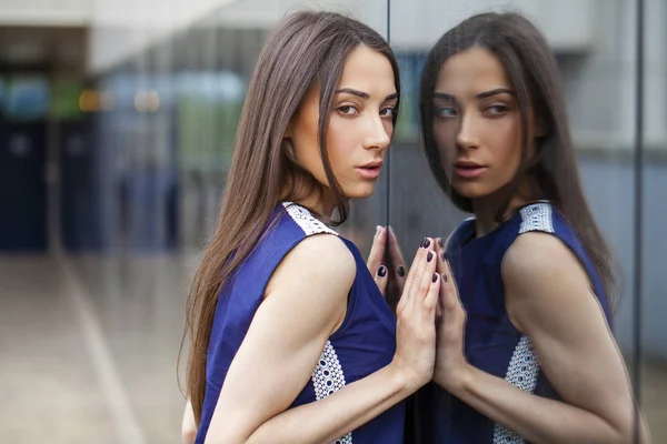 Senhora elegante em vestido azul posando perto de parede espelhada — Fotografia de Stock