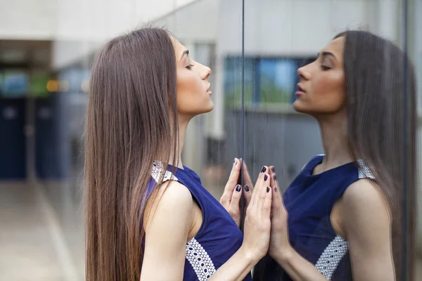 Elegante dama en vestido azul posando cerca de la pared espejada — Foto de Stock