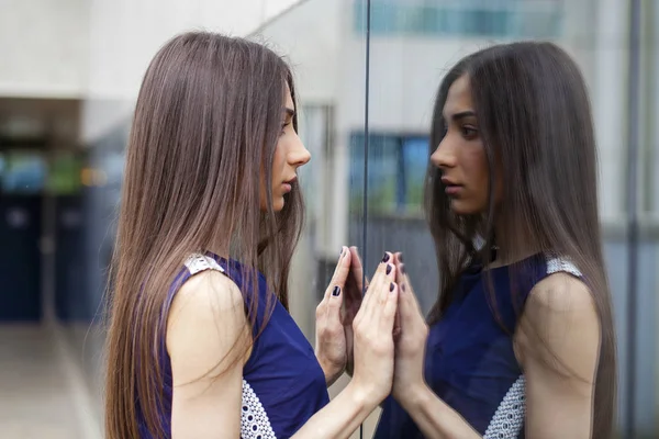 Elegante dama en vestido azul posando cerca de la pared espejada — Foto de Stock