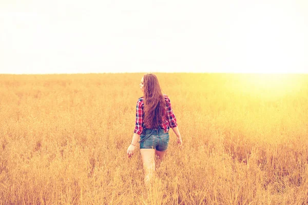 Junge schöne Frau, die in einem Feld spaziert, Sommer im Freien — Stockfoto