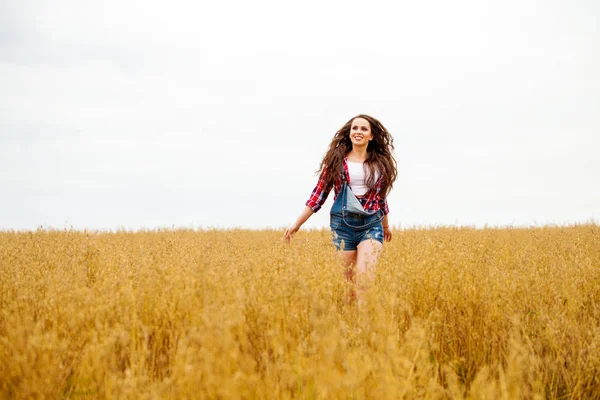 Mooie jongedame wandelen in een veld, zomer in de buitenlucht — Stockfoto