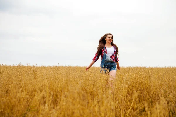 Junge schöne Frau, die in einem Feld spaziert, Sommer im Freien — Stockfoto