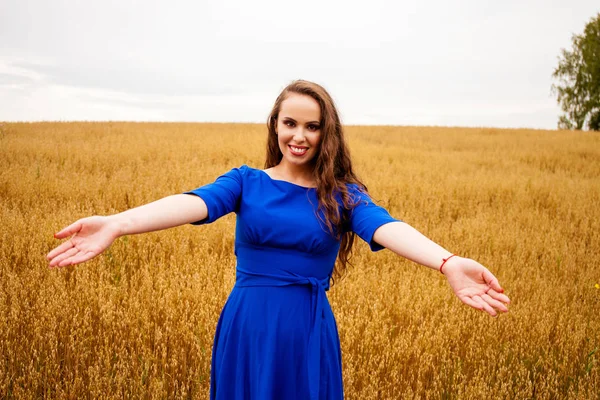 Portret van een jong meisje op een achtergrond van gouden tarweveld — Stockfoto