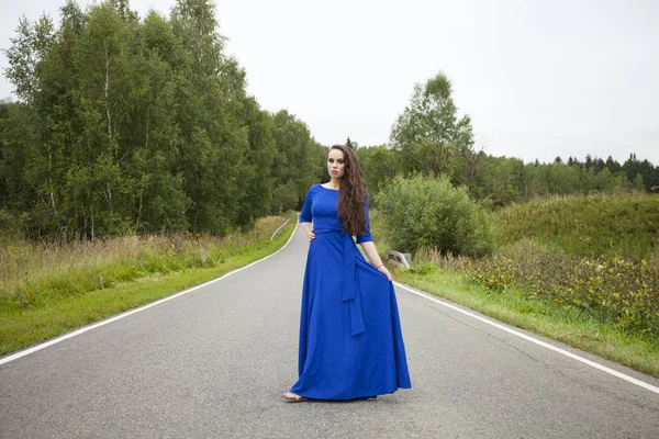 Joven hermosa mujer en un vestido corto azul caminando por el camino —  Fotos de Stock