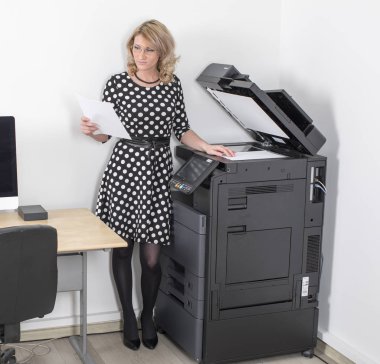 Young beautiful woman making copies in the office clipart