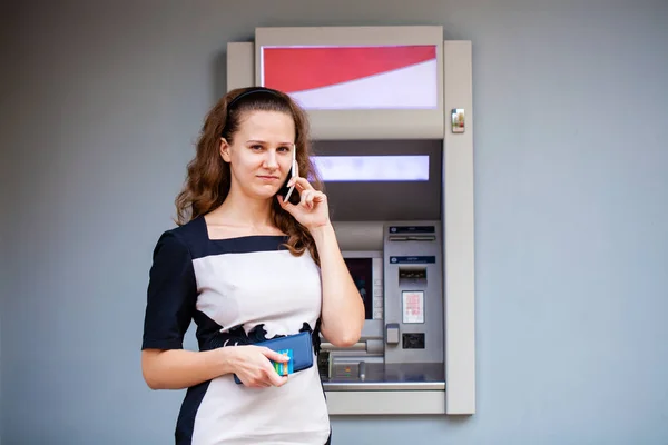 Молодая женщина вставляет кредитную карту в банкомат — стоковое фото