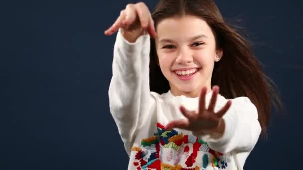 Beautiful happy little girl with arms on the air, isolated blue background — Stock Video