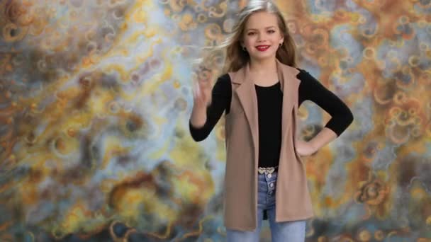 Привітання. Краса блондинка маленька дівчинка позує в студії — стокове відео