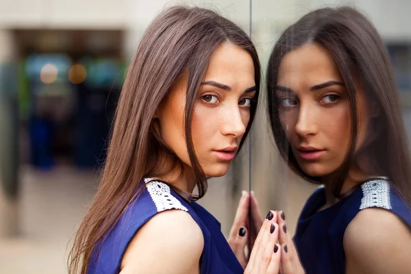 Senhora elegante em vestido azul posando perto de parede espelhada — Fotografia de Stock